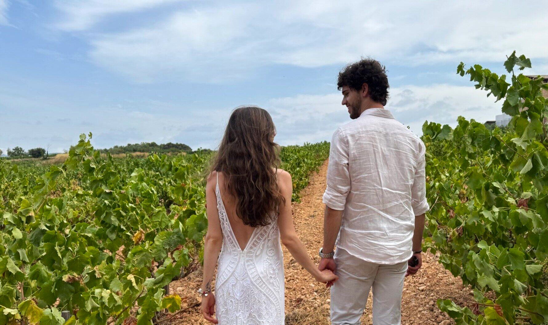 Júlia and Alexandre holding hands, walking through a vineyard